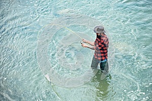 A fisherman with fishing rod on the river. Angler. Difference between fly fishing and regular fishing.