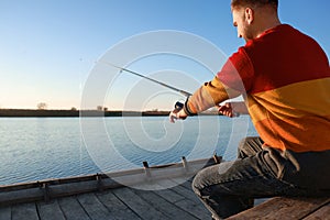 Fisherman with fishing rod at riverside on sunny day