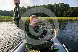 Fisherman fishing rod to fish on the lake with a rubber boat. Hobby.