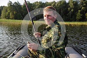 Fisherman fishing rod to fish on the lake with a rubber boat. Hobby.