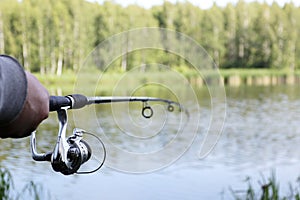 A fisherman with fishing rods, a spinning reel on the river bank. the lake has no focus. Sunrise. Fishing for pike, perch, carp.