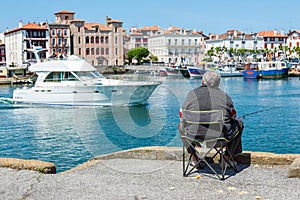 Fisherman fishing in Saint-Jean de Luz - Ciboure harbour. Aquitaine, France.