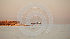 A fisherman is fishing in the sea at dawn, A fisherman on the rock against dawn sky, Silhouettes of fishermen with