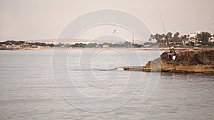 A fisherman is fishing in the sea at dawn, A fisherman on the rock against dawn sky, Silhouettes of fishermen with