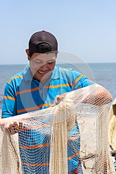 Fisherman fixing his fishing net with rope