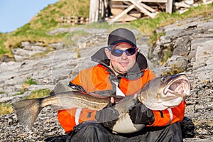 Fisherman in glasses holding big fish on his hands. Smiling