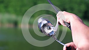 Fisherman hands holding carp fishing rod with reel close up. Angler with rod