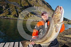 Fisherman happy man holding a huge fish Cod. Pier. horizontal po