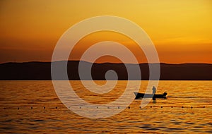 Fisherman on his boat against the sunset background..