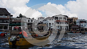 Fisherman and his boat at Lamu Island, Kenya.  A row of seafacing hotels and other buildings are visible in the background