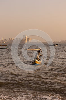 A fisherman on his boat and pushing it to sea