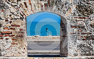 Fisherman on his boat seen through the embrasure of the city walls in the Cartagena
