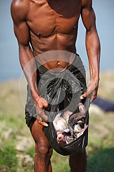 Fisherman with his catch in longyi, Myanmar