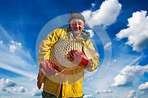 Fisherman Holding a Big Fish Against Blue Sky and Clouds