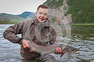 A fisherman holding a big taimen trout caught on a river in Mongolia, Moron, Mongolia photo