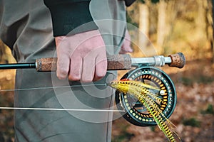 Fisherman holds fly fishing rod