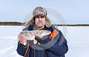 fisherman holds trophy pike Esox lucius . Winter fishing, ice lake