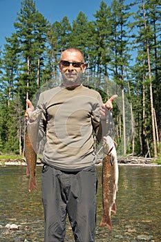 Fisherman holds up two large fish.