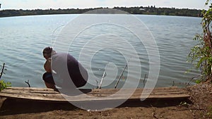 A fisherman hooked a fishing rod with a fish trying to stretch it on a hot summer day on the shore of a pond