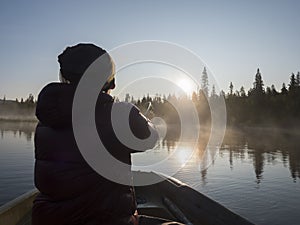 Fisherman man in rowing boat at lake Sjabatjakjaure in Beautiful sunny morning haze mist in Sweden Lapland nature. Mountains,