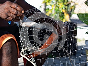 Fisherman man sitting repairing fishing net. Sustainable work