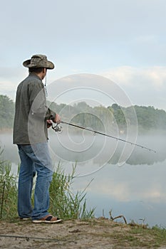 Fisherman on a morning foggy lake