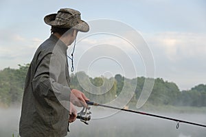 Fisherman on a morning foggy lake