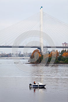 Fisherman on motor boat near the Big Obukhovsky cable-braced bridge, St. Petersburg, Russia