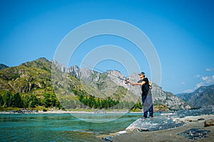 Fisherman on the mountain river at the nice summer day. Trout fly fishing in the mountain river with mountains in background