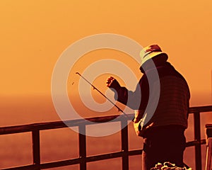 Fisherman on pier at sunset