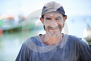 Fisherman, portrait and rugged man with smile, harbour and wrinkles from sunlight exposure. Boats, ships and water or