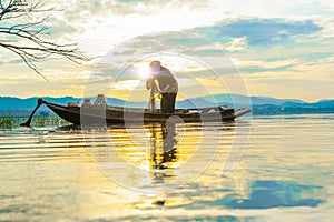 Fisherman prepare fishnet in old boat on lake early morning