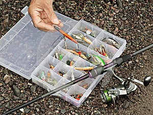 The fisherman prepares lures, wobblers and other fishing equipment. Preparation for fishing. A fishing tackle box