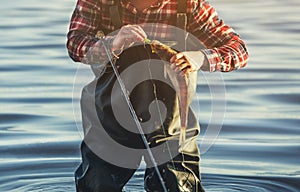 The fisherman in the red shirt is holding a fish Zander caught on a hook