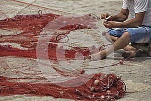 Fisherman repairs his net