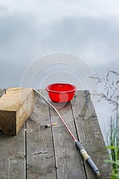 Fisherman`s equipment on a wooden bridge on the background of a river. Fishing rod on the pier