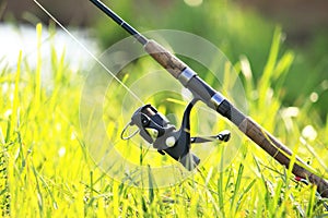 Fisherman`s fishing rod with inertia-free coil in summer on shore of lake