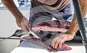 Fisherman`s hands with knife when processing tuna meat after fishing