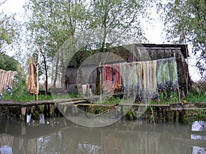 Fisherman\'s hut on the bank of a muddy river. Fishing nets hang on stands. A neglected place