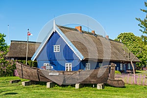 Fisherman`s museum. Beautiful old Lithuanian traditional wooden blue houses with thatched roof and old boat