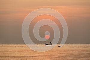 fisherman sailing the boat under a big red sundown