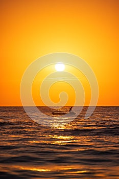 Fisherman sailing with his boat on beautiful sunrise over the sea