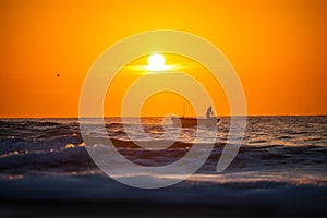 Fisherman sailing with his boat on beautiful sunrise over the sea