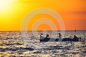 Fisherman sailling with his boat on beautiful sunrise over the sea