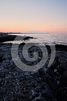 Fisherman by the sea at sunset. twilight silhouettes of people in the distance