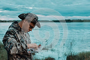 Fisherman selecting one bait from accessory box near river