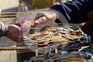 A fisherman sells sun dried fish