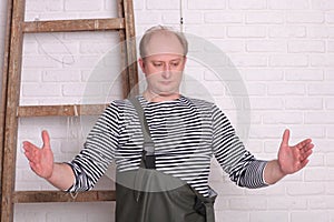 Fisherman shows hands the size of fish on white wall background.