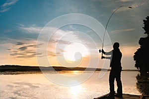 A fisherman silhouette fishing at sunset. Freshwater fishing, catch of fish.