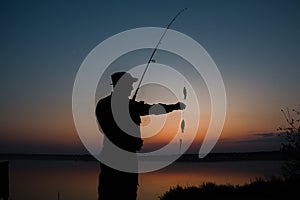 A fisherman silhouette fishing at sunset. Freshwater fishing, catch of fish